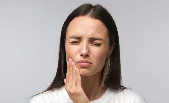 Stock image of a model touching her mouth with pain by closing eyes