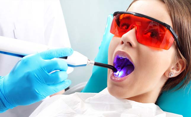 Stock image of a dental patient with mouth wide open having a laser treatment